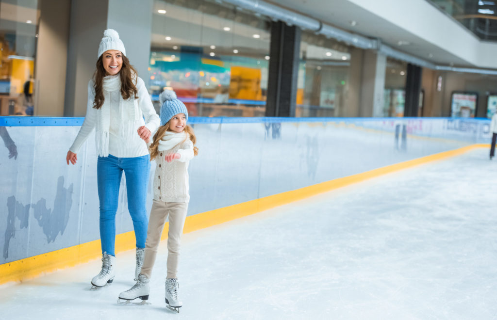 Smiling,Mother,And,Daughter,Holding,Hands,And,Skating,On,Ice
